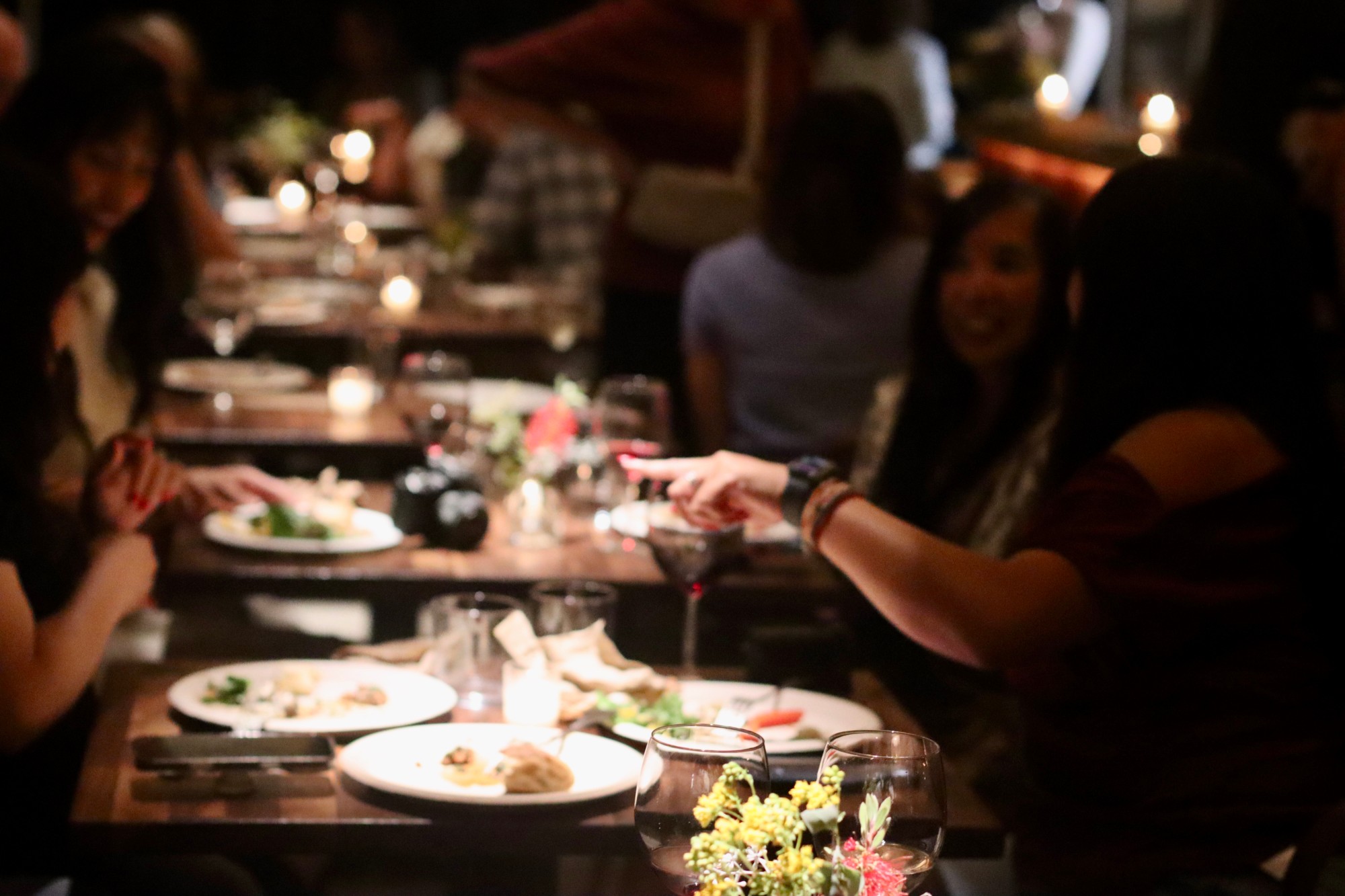 Guests sharing plates and wine by candlelight